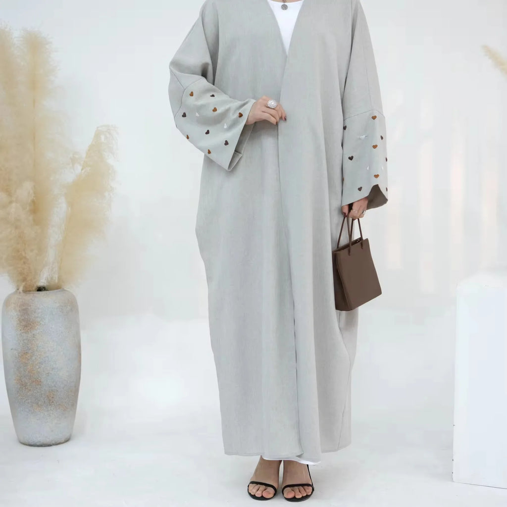 عباية كيمونو بتصميم واسع وأكمام بات، مصنوعة من الكتان الطبيعي الفاخر لتوفير راحة مثالية ل 2024. تتميز بتطريز قلوب أنيق يعكس الذوق الرفيع،